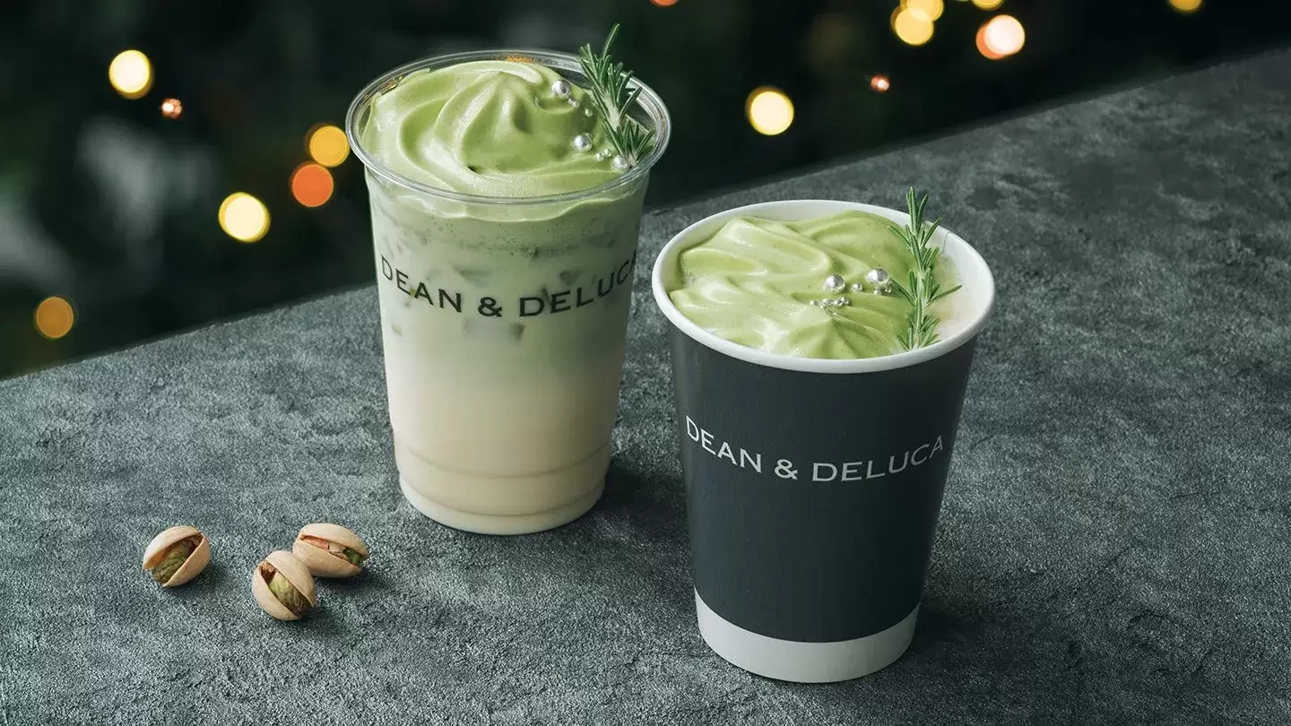 DEAN & DELUCAの抹茶ラテとピスタチオの写真。ラテは緑色の泡で覆われ、ローズマリーと銀色の装飾が施されています。ピスタチオが添えられています。
