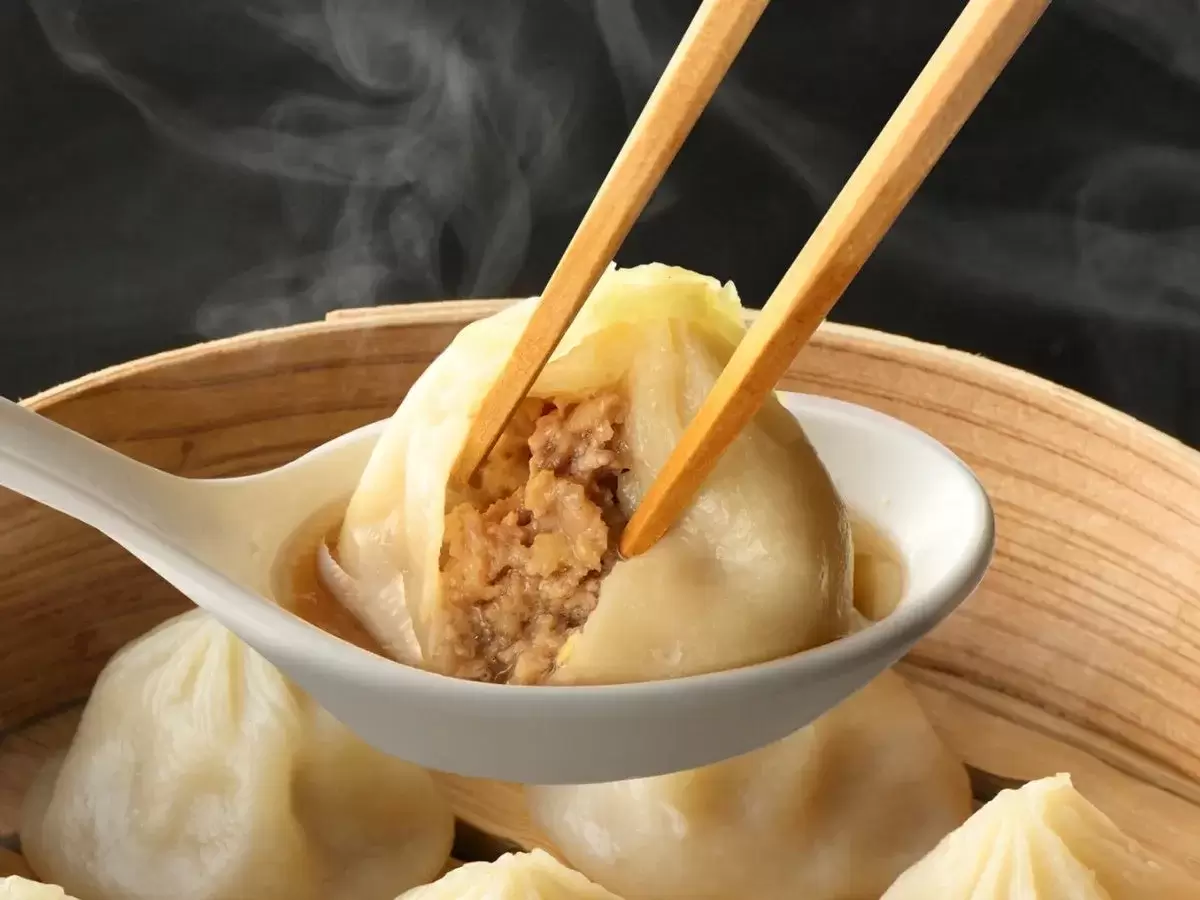 蒸し餃子を箸で持ち上げ、スプーンに入れた写真。