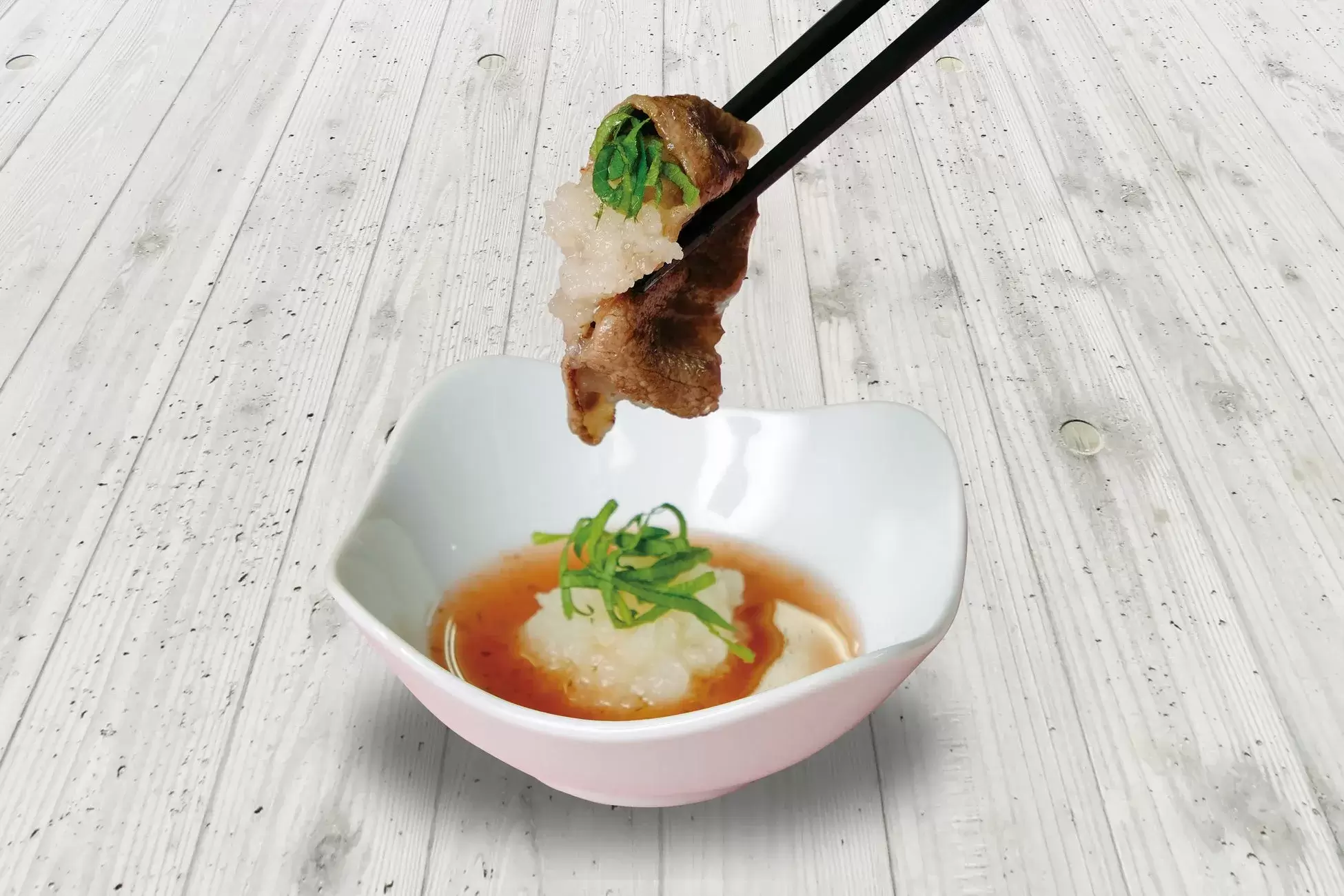 箸で持たれた牛肉の巻物と梅おろしダレ