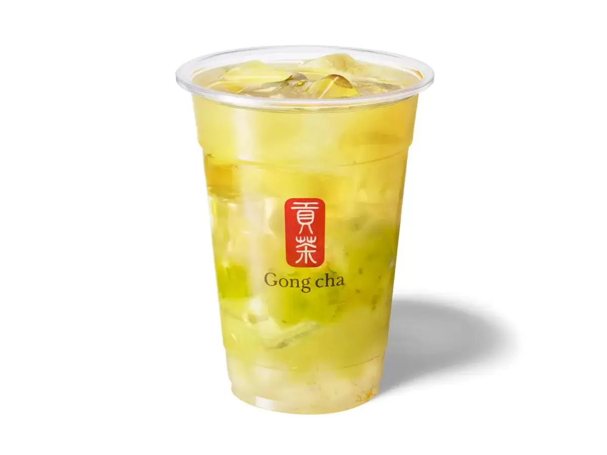 透明なプラスチックカップに入った、緑色のアイスティーのクローズアップ写真。ロゴがカップに印刷されています。